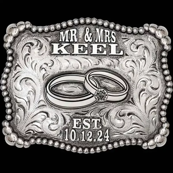 "The monochromatic design of our Silverado Belt Buckle is simply classic and leaves the story to be told with memories of your Special Day. This Buckle is crafted on a hand-engraved, German Silver base with a light antique finish. It is detailed with